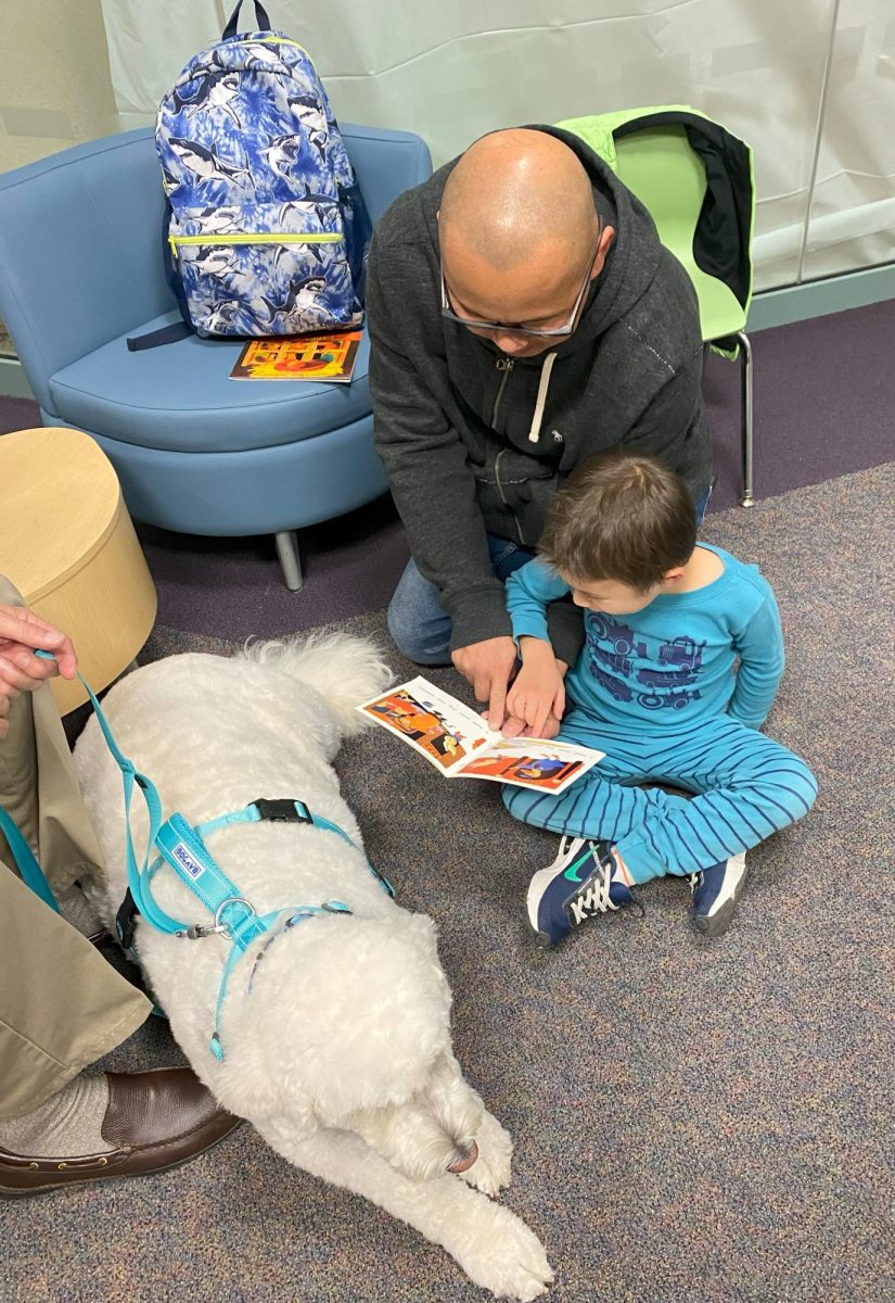 Kai Luu, reads to Abby, a trained therapy dog, with the help of his dad, Thuan, at R.H. Stafford Library in Woodbury.