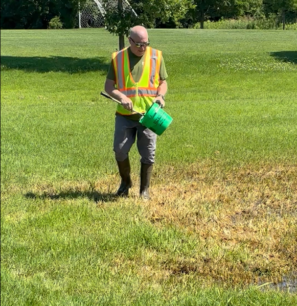 Christensen spreads treatment on a mosquito breeding area at Ojibway Park.