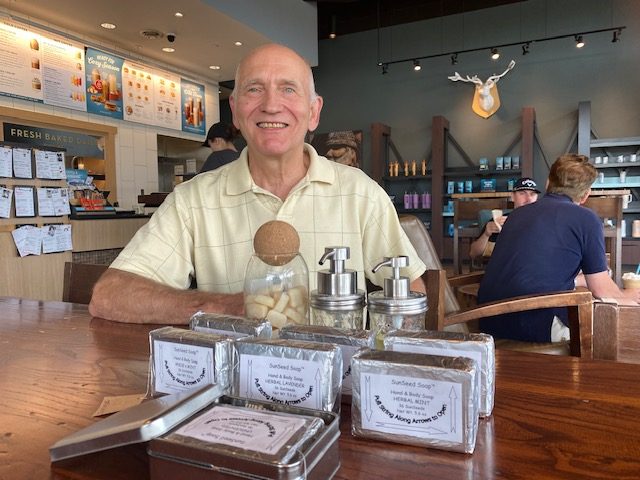 Retired 3M chemist Jim McDonell with a display of his Sun Seed Soap products at a local coffee shop last week.
