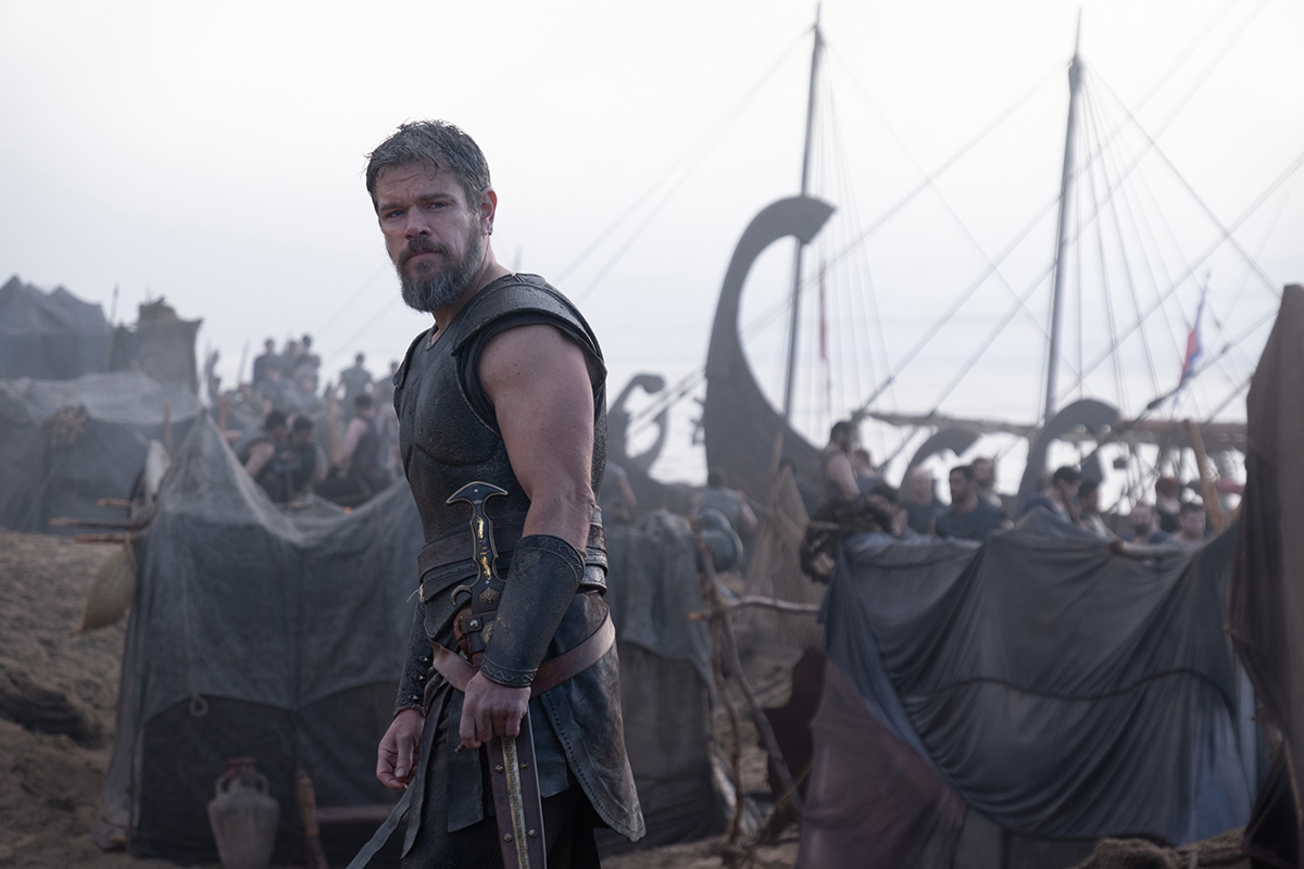 A Greek solider stands on the beach in front of a large boat